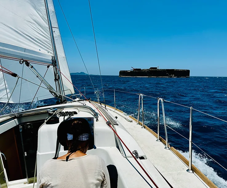 Student steering a cruising yacht under sail on open water