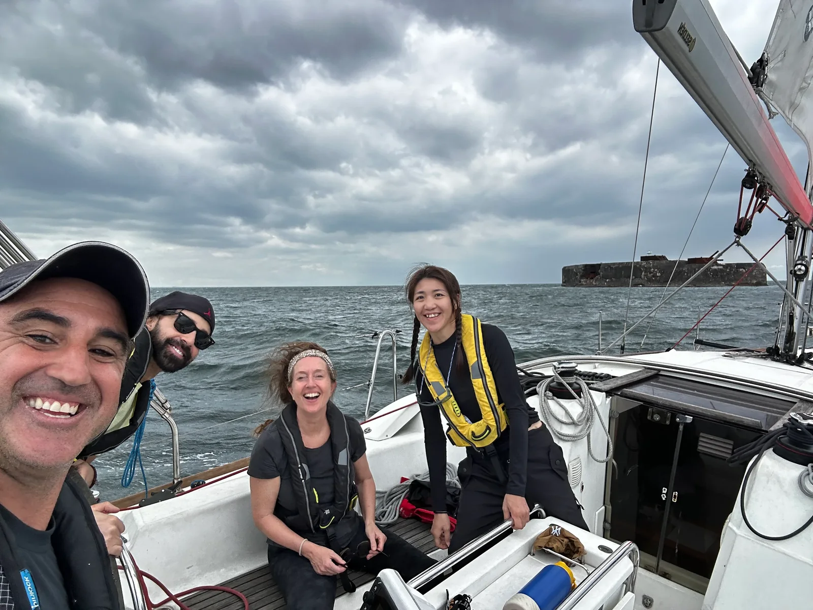 Group of crew in life jackets and light layers gathered in a yacht cockpit