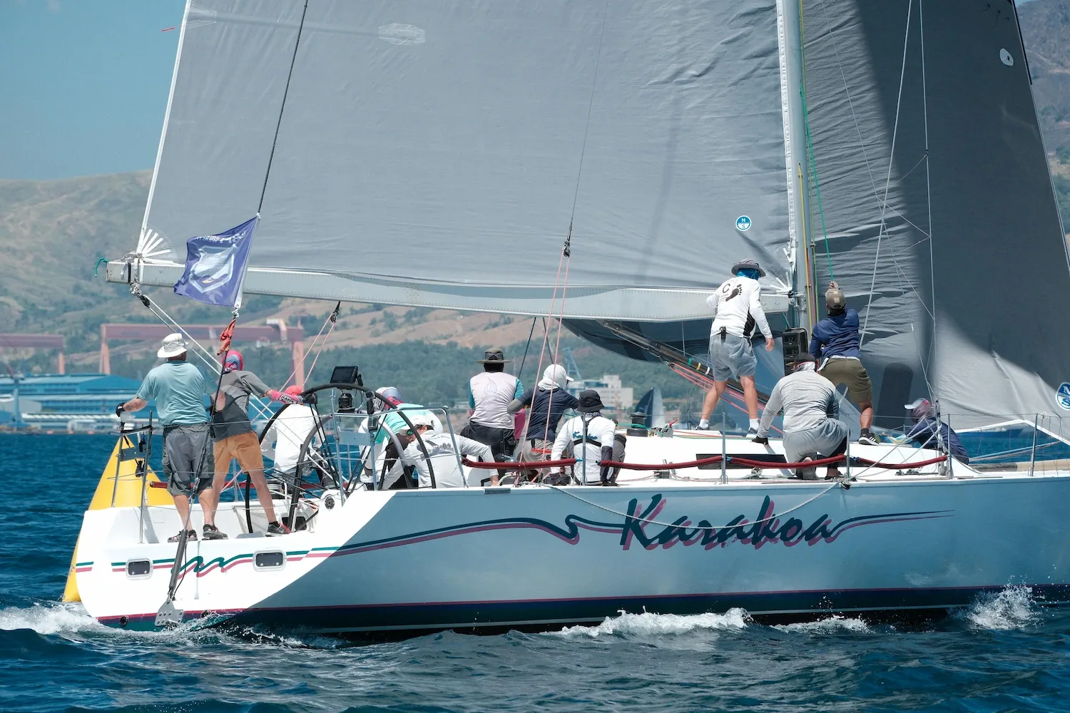 Full crew working the deck of a keelboat during a regatta start