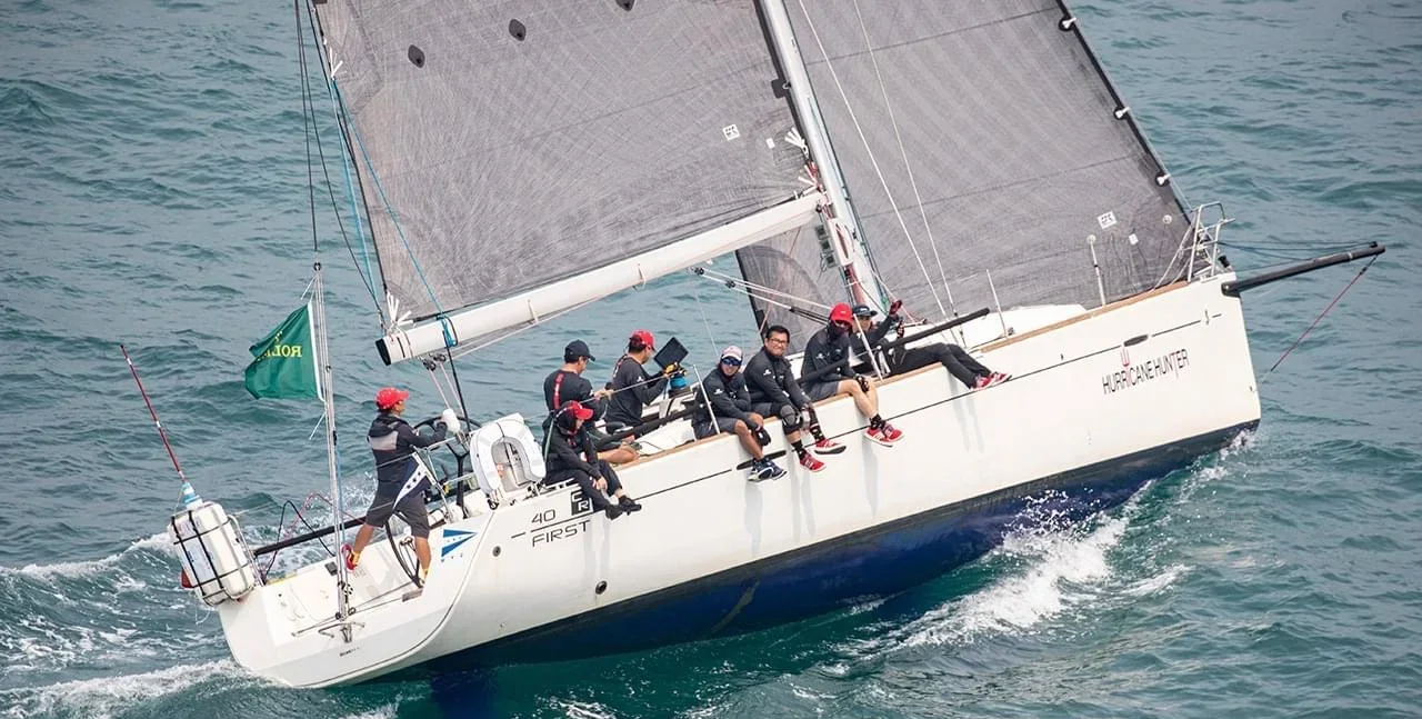 Racing yacht sailing upwind with full crew hiking out on a breezy day