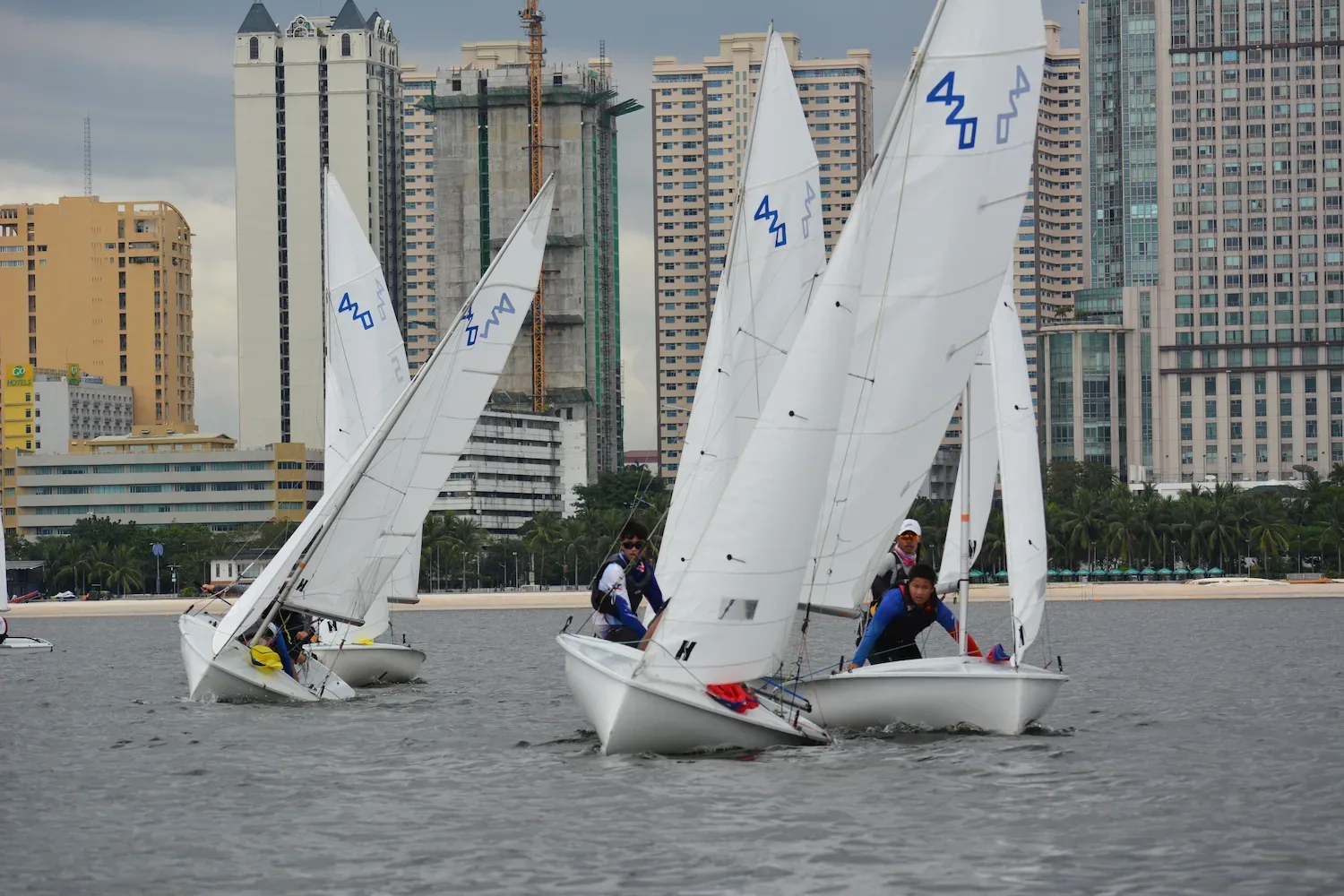 420 class training dinghies sailing in front of a city waterfront skyline